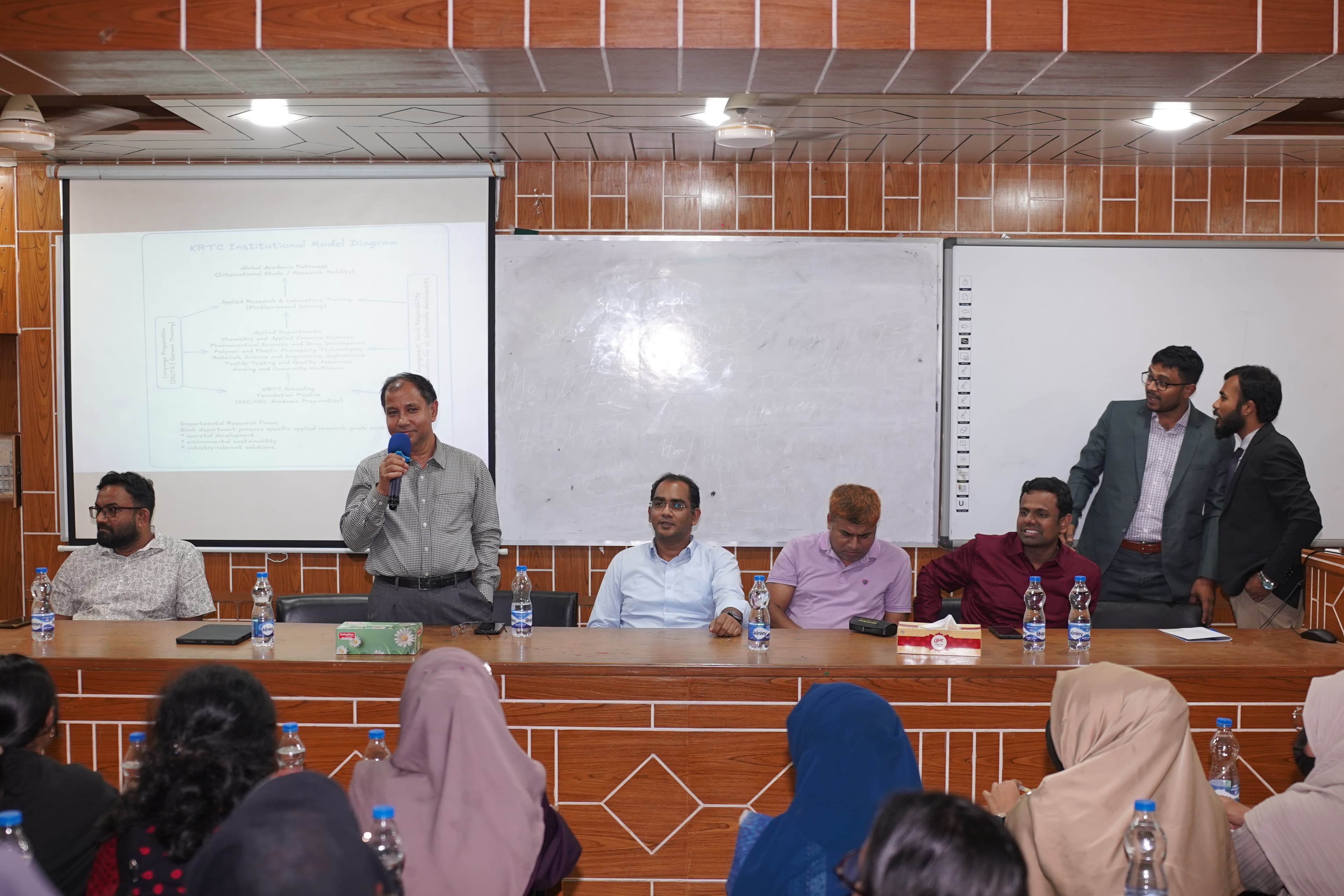 Distinguished academic guests seated and speaking at the seminar